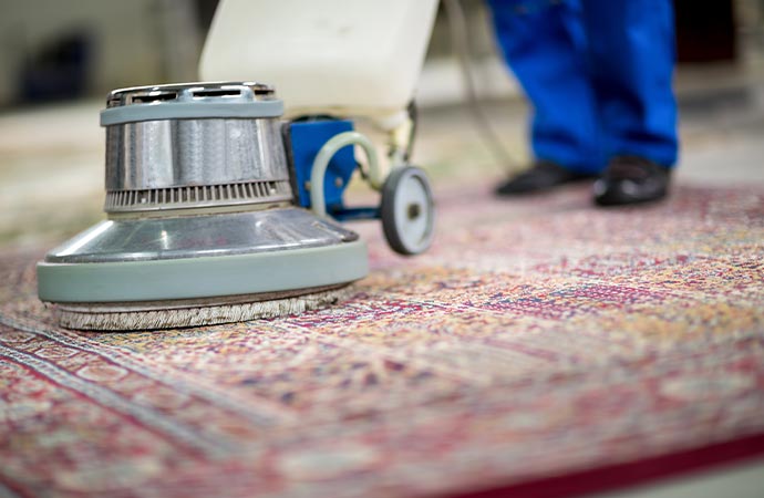 Worker dusting a rug for a cleaner appearance